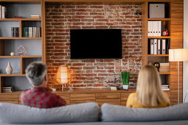 A couple enjoying their wall-mounted TV in a clean living room